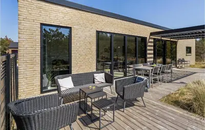 a wooden deck with chairs and tables and windows at Three-Bedroom Holiday Home In Thisted in Thisted