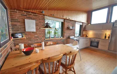 a kitchen with a wooden table and a brick wall at Three-Bedroom Holiday Home In Struer in Struer