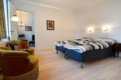 a bedroom with a bed and a living room at Strømpehuset in Øster Assels
