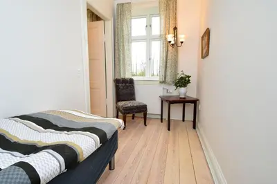 a bedroom with two beds and a chair and a window at Strømpehuset in Øster Assels
