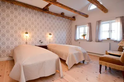 a room with two beds and a chair and windows at Strømpehuset in Øster Assels