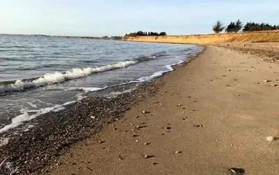 a sandy beach with waves coming in from the ocean at Strømpehuset in Øster Assels