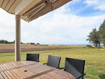 a wooden table and chairs with a view of a field at 8 person holiday home in Spøttrup in Spottrup