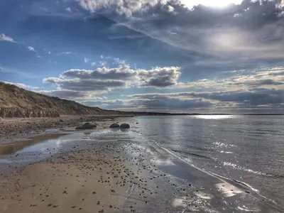 a beach with rocks in the water under a cloudy sky at 8 person holiday home in Spøttrup in Spottrup