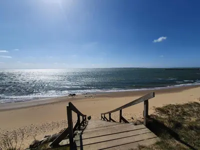 a wooden staircase leading to a beach with the ocean at 8 person holiday home in Spøttrup in Spottrup