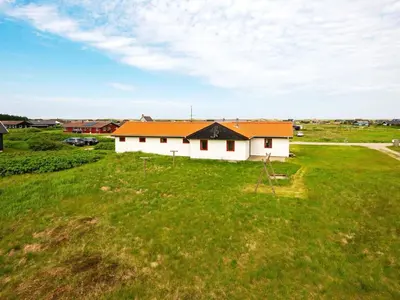 a white house with an orange roof in a field at 10 person holiday home in Harboøre-By Traum in Harboør