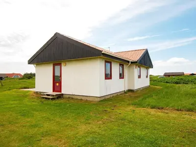 a small white house with a black roof in a field at 10 person holiday home in Harboøre-By Traum in Harboør
