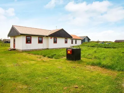a house in a field with a trash can at 10 person holiday home in Harboøre-By Traum in Harboør