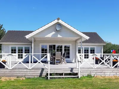 a white house with a porch with a table and chairs at Modern Retreat at Knud Strand - By Traum Ferienwohnungen in Spottrup