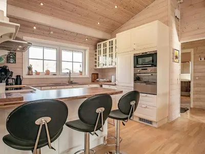 a kitchen with white cabinets and black bar stools at Modern Retreat at Knud Strand - By Traum Ferienwohnungen in Spottrup