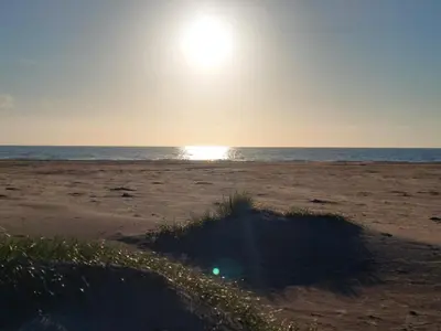 a beach with the sun rising over the ocean at 10 person holiday home in Løkken-By Traum in Løkken