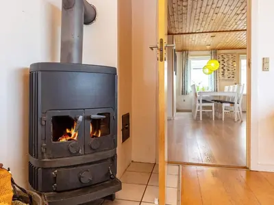 a stove in a living room with a table at Panoramic Seaside Escape - By Traum Ferienwohnungen in Frøstrup
