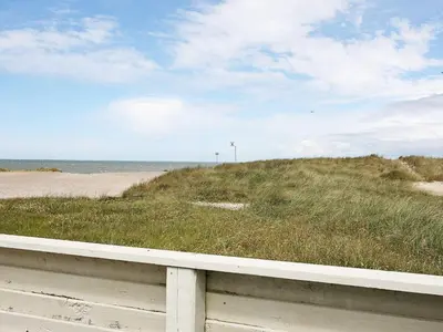 a field of grass next to a sandy beach at Panoramic Seaside Escape - By Traum Ferienwohnungen in Frøstrup