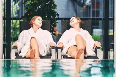 two women sitting in chairs next to a pool at Hotel Thinggaard in Hurup