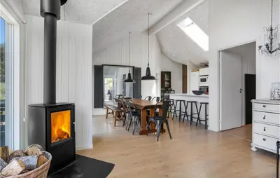 a kitchen and dining room with a fireplace in a house at Lovely Home In Blokhus With Sauna in Blokhus