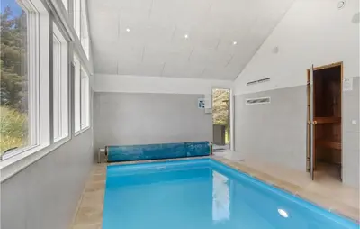 a swimming pool in a room with a large window at Lovely Home In Blokhus With Sauna in Blokhus