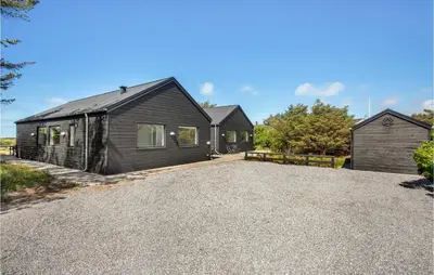 a house with a gravel driveway in front of it at Lovely Home In Blokhus With Sauna in Blokhus