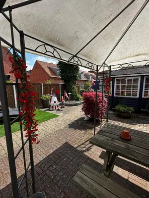 a patio with a wooden picnic table and red flowers at Oasen in Viborg
