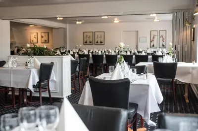a dining room with white tables and chairs at Rønnes Hotel in Fjerritslev