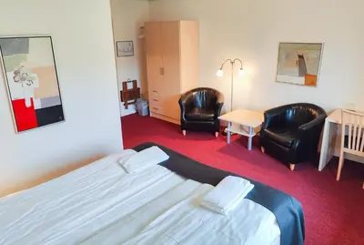 a hotel room with a bed and two chairs at Rønnes Hotel in Fjerritslev