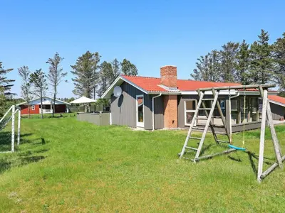 a yard with two swings in front of a house at 10 person holiday home in Løkken-By Traum in Løkken