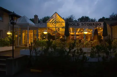 a building with a restaurant with tables and umbrellas at Rold StorKro in Skorping