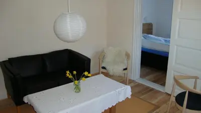 a living room with a table and a black leather couch at Klosterpensionen in Viborg