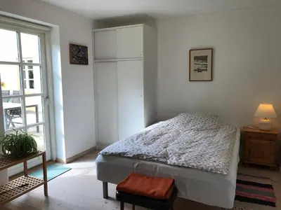 a white bedroom with a bed and a window at Tranum Lys og Glas in Brovst