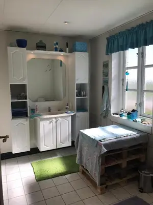 a bathroom with white cabinets and a green rug at Tranum Lys og Glas in Brovst