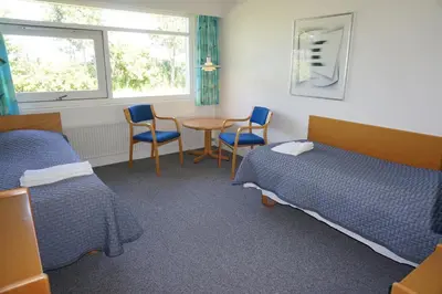 a room with two beds and a table and chairs at Motel Spar 10 in Viborg