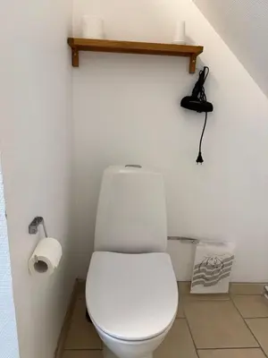 a bathroom with a toilet with a phone on the wall at Guesthouse Hune in Blokhus