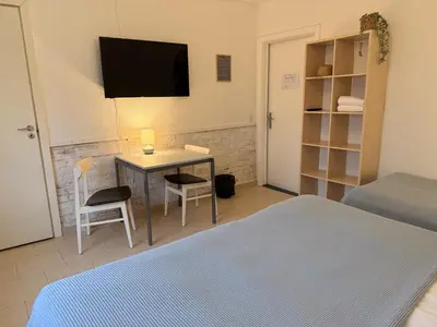 a bedroom with a bed and a desk with a television at Guesthouse Hune in Blokhus