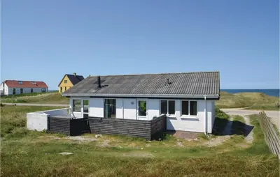 a small white house on the side of a field at Three-Bedroom Holiday Home In Frostrup in Frøstrup