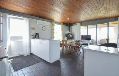 a kitchen with white cabinets and a dining room at Three-Bedroom Holiday Home In Frostrup in Frøstrup
