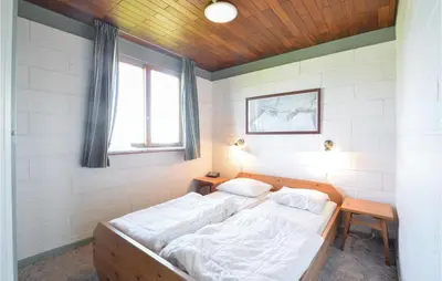 a bedroom with a bed with white sheets and a window at Three-Bedroom Holiday Home In Frostrup in Frøstrup