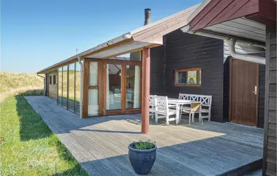 a house with a deck with a table and chairs at Five-Bedroom Holiday Home In Lokken in Løkken