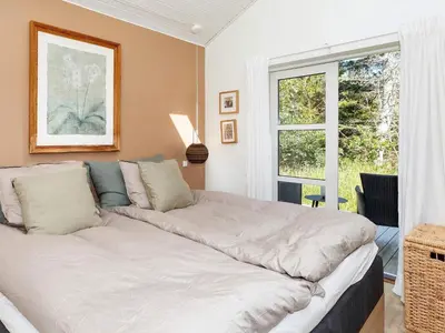 a large bed in a room with a window at 6 person holiday home in Blokhus-By Traum in Blokhus
