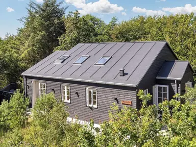 a black house with solar panels on the roof at 6 person holiday home in Blokhus-By Traum in Blokhus