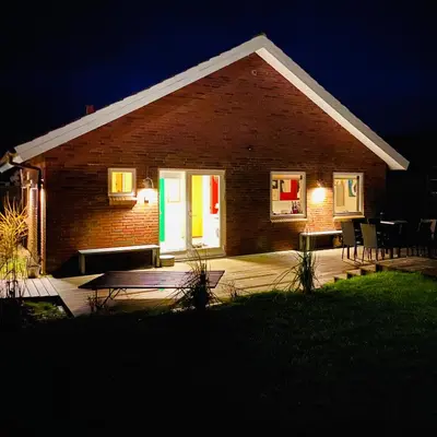 a brick house with a porch at night at Hyggeligt byhus ved glasværkstedet på Nordmors in Sejerslev