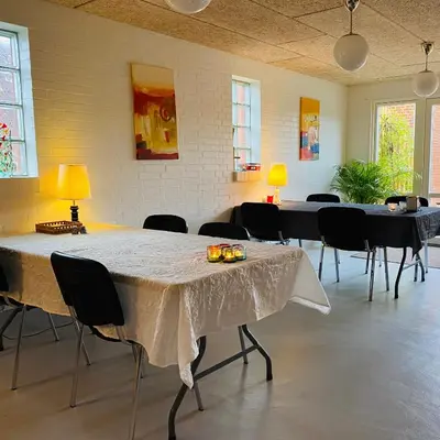 a large room with tables and chairs and lamps at Hyggeligt byhus ved glasværkstedet på Nordmors in Sejerslev