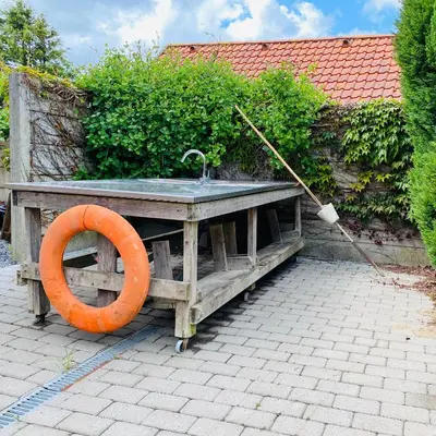 a wooden sink with an orange ring next to a hedge at Hyggeligt byhus ved glasværkstedet på Nordmors in Sejerslev
