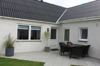 a patio with a table and chairs in front of a house at Motel Hune Apartments in Blokhus
