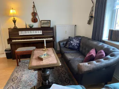 a living room with a leather couch and a piano at Motel Hune Apartments in Blokhus