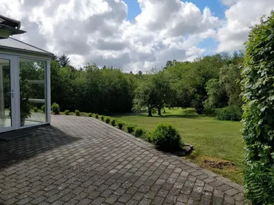a brick driveway leading to a garden with trees at Bændal in Bækmarksbro