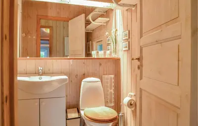 a bathroom with a toilet and a sink and a mirror at Four-Bedroom Holiday Home In Lokken in Løkken