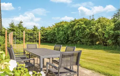a wooden table and chairs in a yard at Four-Bedroom Holiday Home In Lokken in Løkken