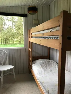 a bunk bed in a room with a chair and a window at Summer cottage in Nøreng