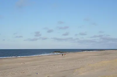 a beach with people walking on the sand and the ocean at Luksus-poolhus B5 in Harboør