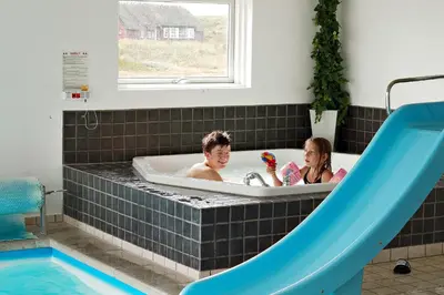 a boy and a girl in a bath tub with a slide at Luksus-poolhus B5 in Harboør