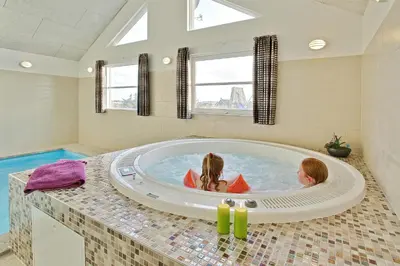 two children in a jacuzzi tub in a bathroom at Luksus-poolhus L21 in Harboør